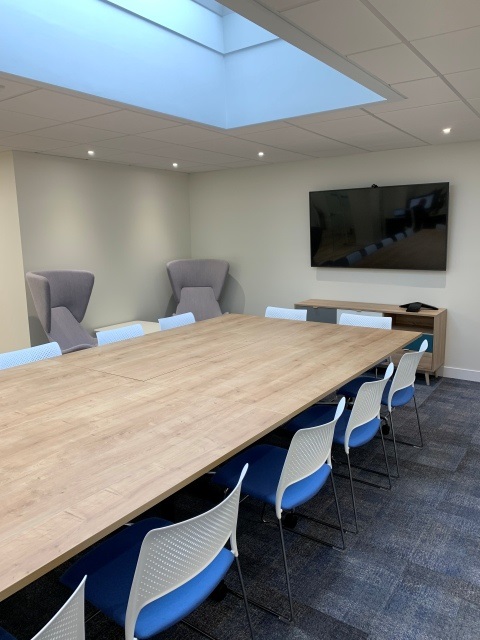 Rectangular meeting table and chairs in a room with a wall mounted screen 