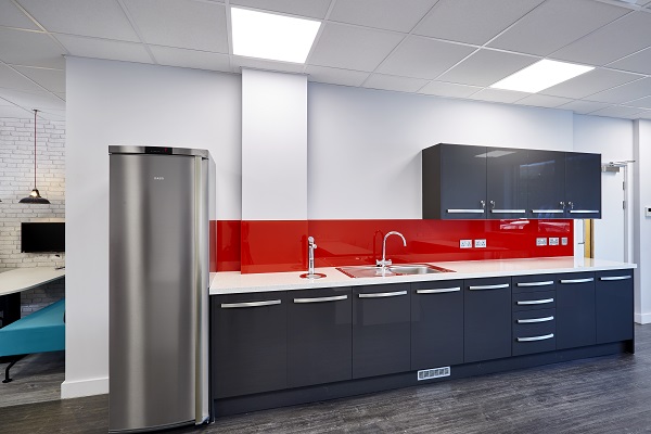 Dark grey kitchen cabinets, red splashback and tall stainless steel fridge